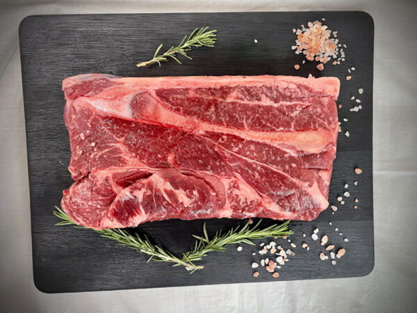 slab of beef sitting on a black cutting board with herbs and spices